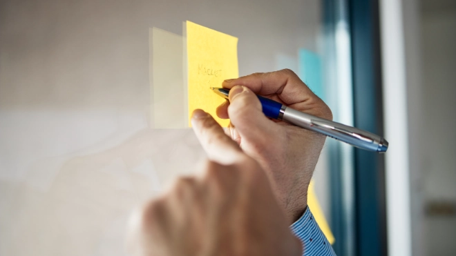 hands writing on post it note