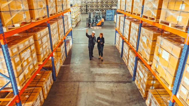 Two female workers inspecting large warehouse racks