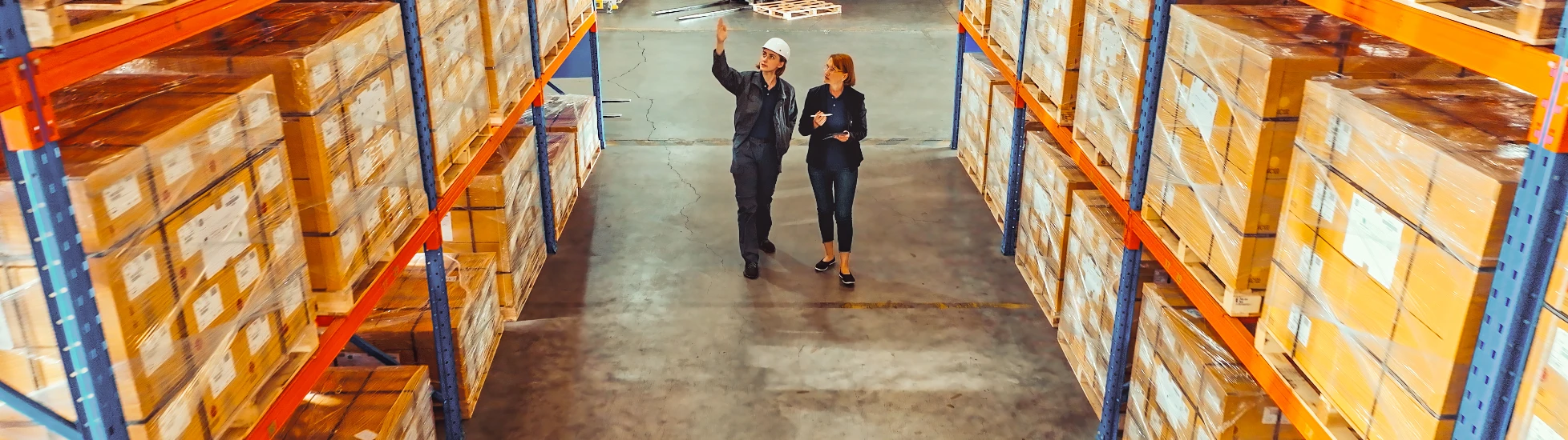 Two female workers inspecting large warehouse racks